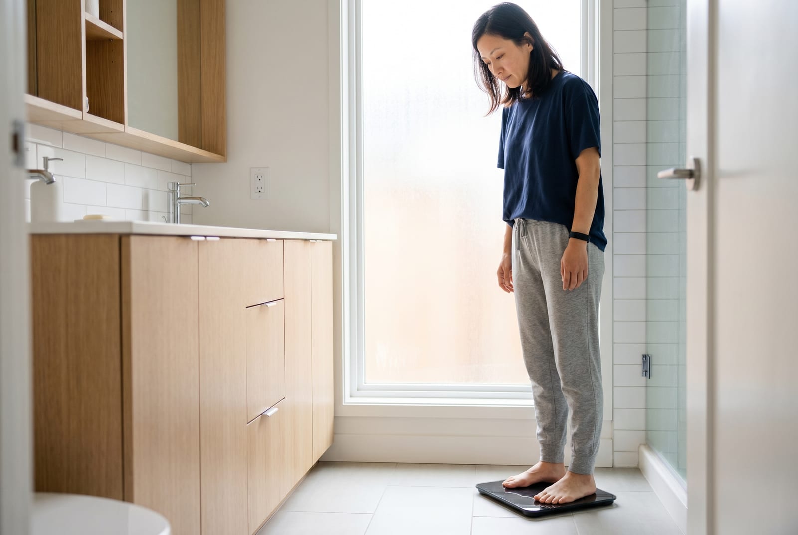 女士在柔和灯光的浴室里走下智能体重秤，瞥了一眼读数 - AI 生成